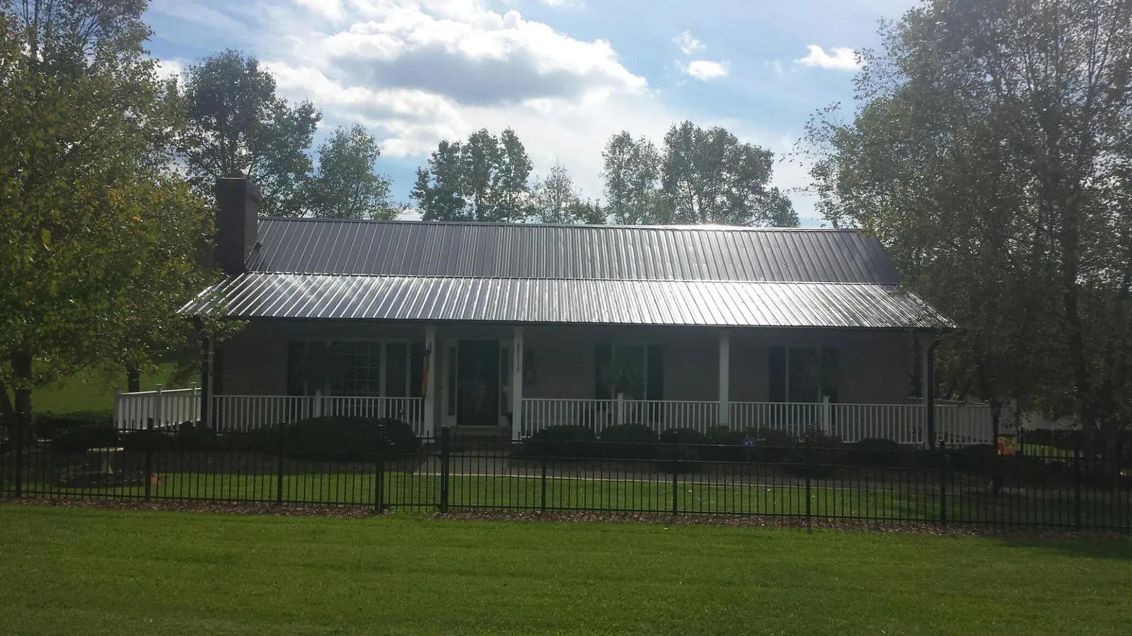 Gray metal roof on a brick ranch with a full width front porch — Gutter Guard Installation work by our crew in Brookhaven