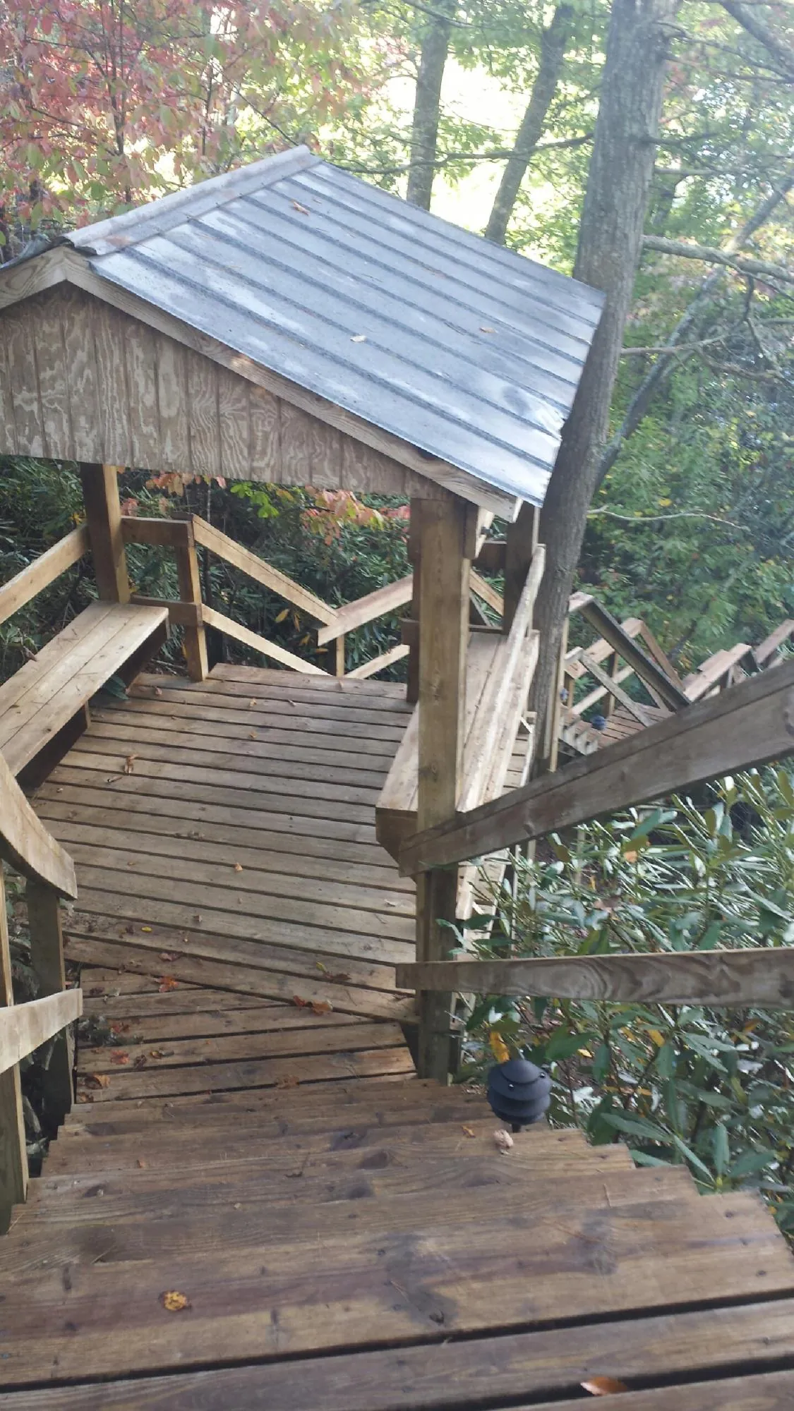Metal roofed shelter over wooden steps on a wooded walkway — Skylight Repair & Installation work by our crew in Brookhaven
